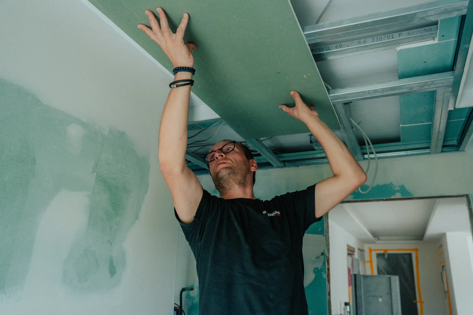 Mitarbeiter montiert eine Gipskartonplatte an der Decke