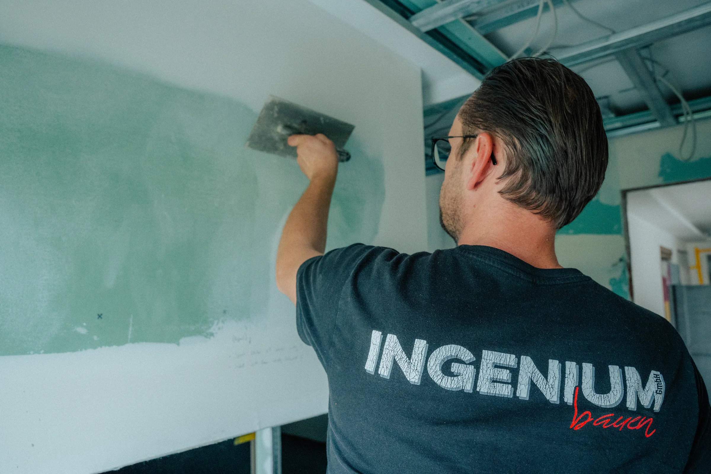 Mitarbeiter der INGENIUM Bauen GmbH beim Verspachteln einer Trockenbauwand